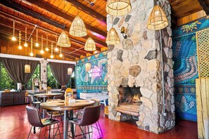 A restaurant interior with stone walls, hanging lights, and a fireplace.