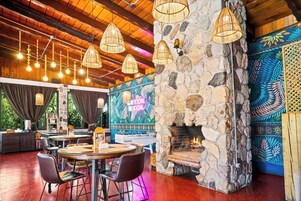 Interior de restaurante con paredes de piedra, luces colgantes y chimenea.