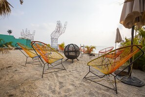 A beach with colorful wire mesh chairs, a spherical sculpture, and umbrellas. - Socialtel Atitlan (Panajachel)