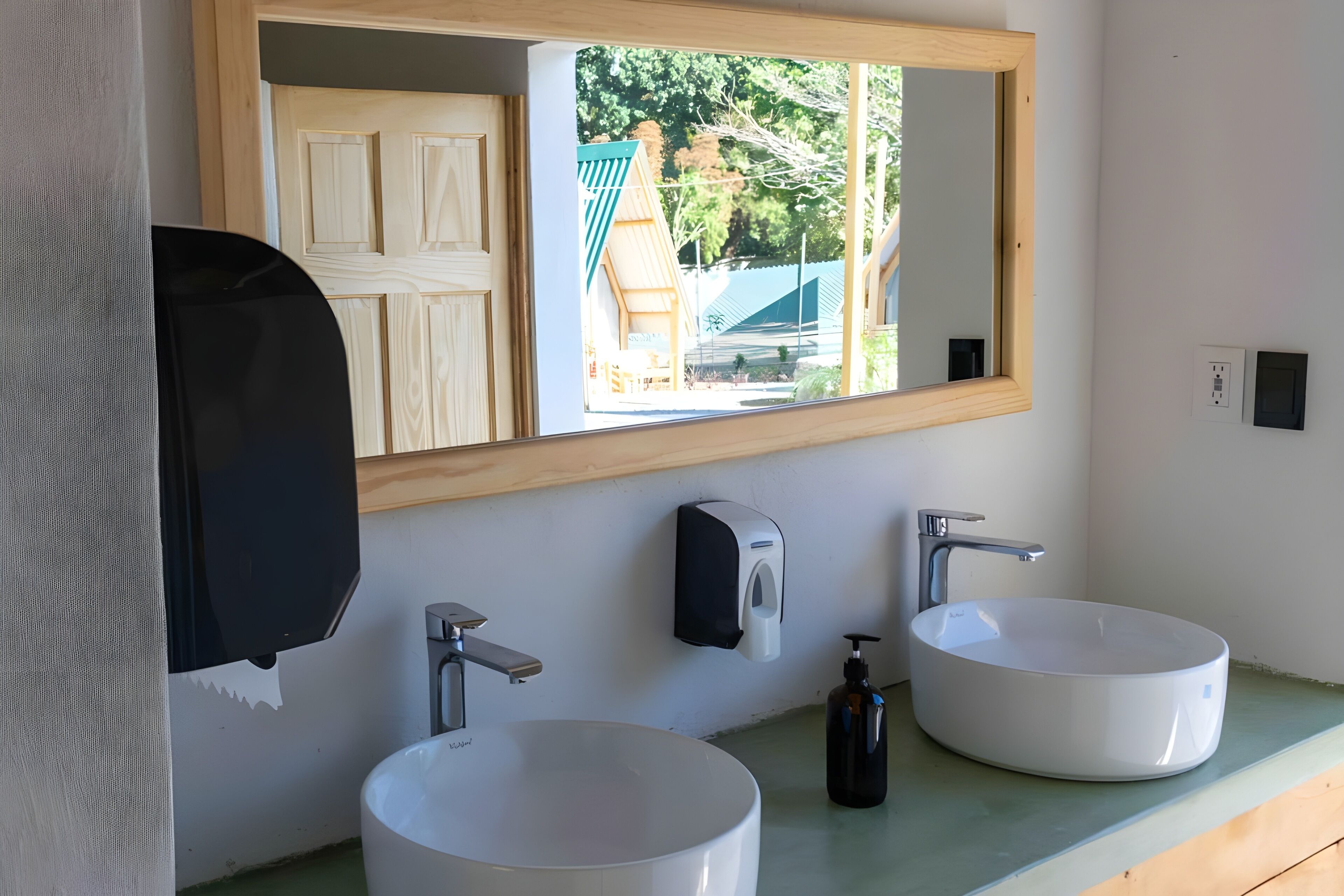 A bathroom with two sinks, a soap dispenser, and a mirror.