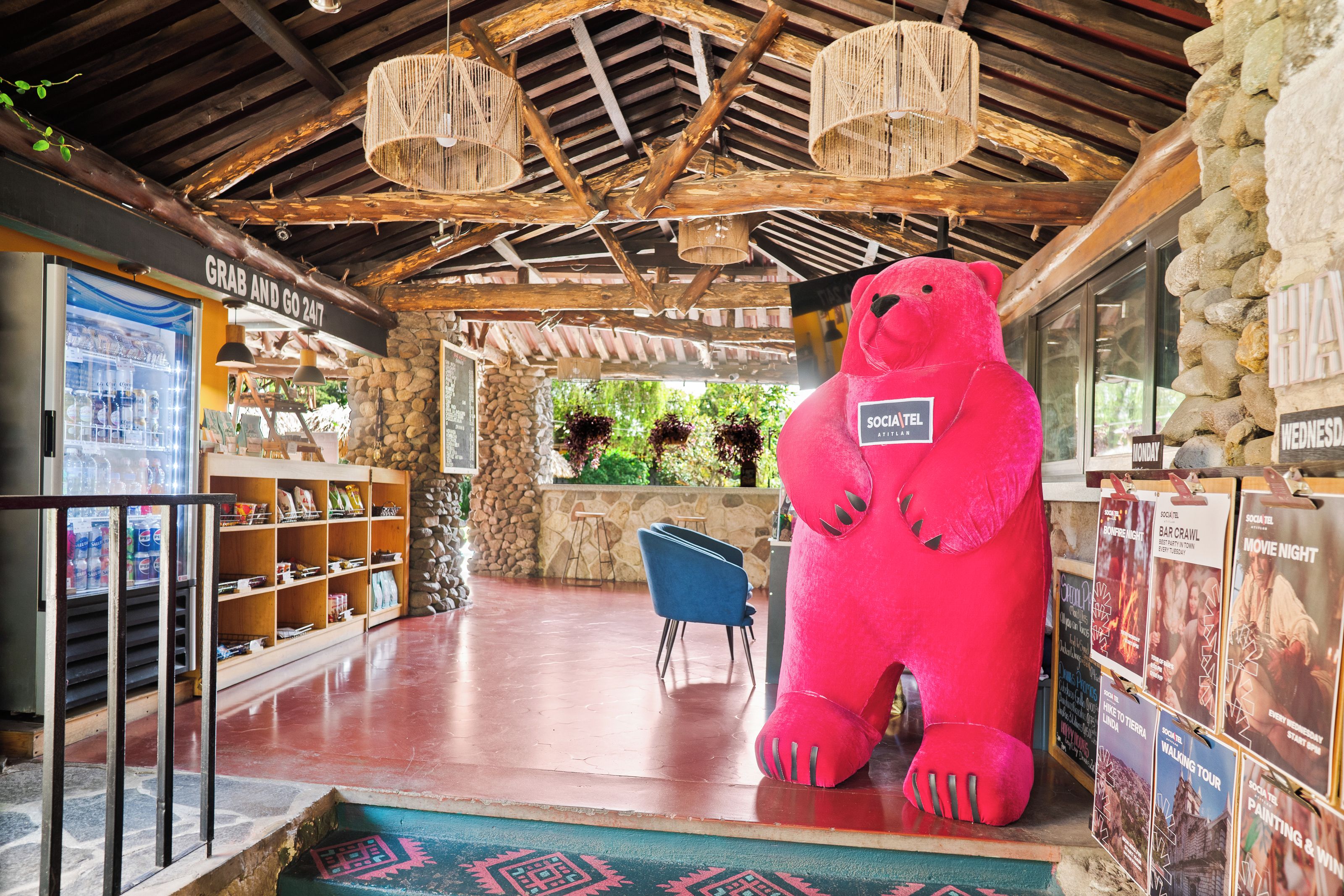 A spacious lobby with a large red bear sculpture, wooden ceiling beams, stone walls, and a seating area.