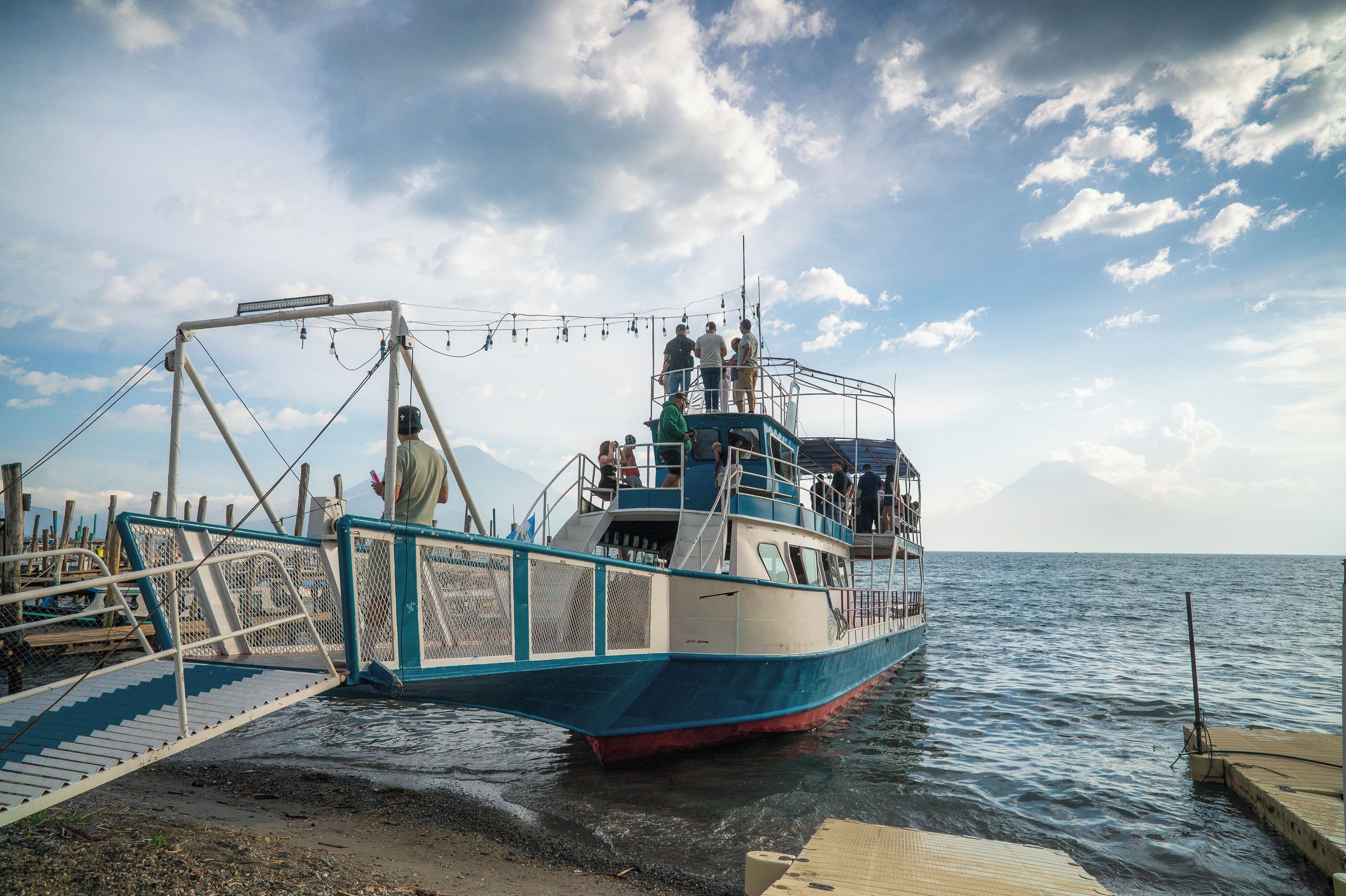 A boat docked at a pier with a metal railing and a staircase leading up to the deck.