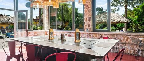 Un restaurante con una mesa grande, sillas rojas y lámparas colgantes.