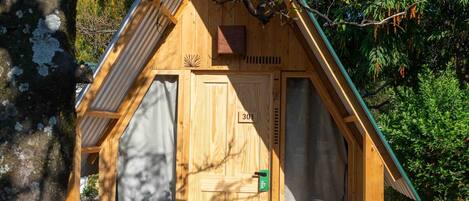 A wooden cabin with a sloped roof, a wooden door, and a small porch area with a bench.