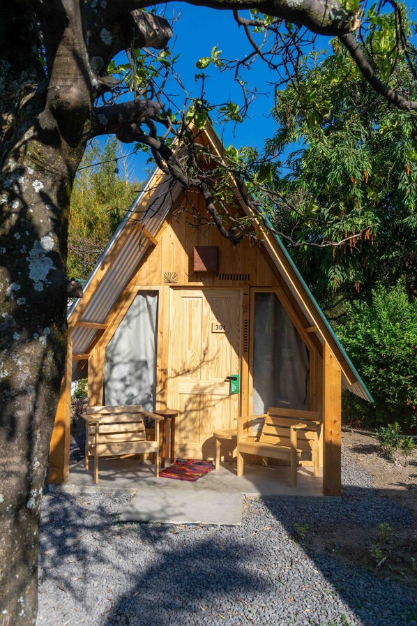Une cabane en bois avec un toit en pente, une porte en bois et un petit porche doté d’un banc.
