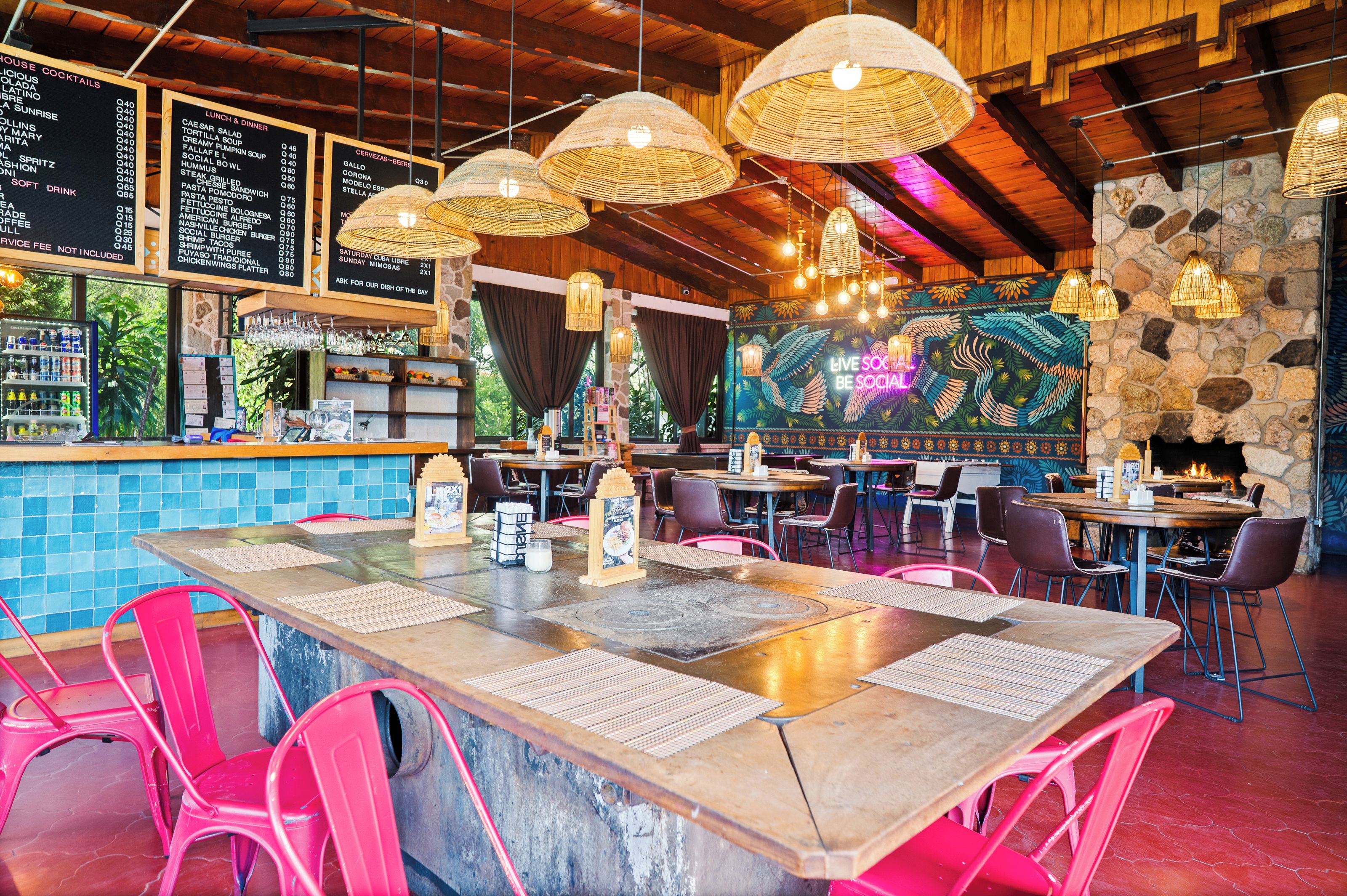 A restaurant interior with a bar area, wooden tables, and hanging wicker lamps.