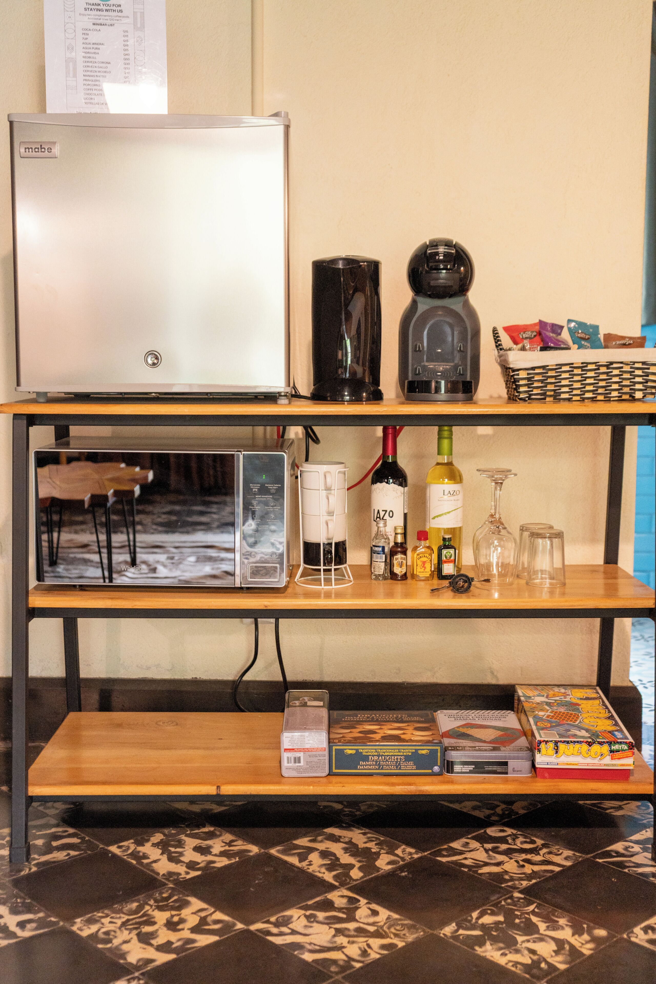 A kitchen area with a refrigerator, coffee maker, and wine bottle.