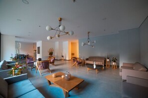 A modern living room with a sofa set, a coffee table, and a dining area with chairs. - Hotel Class Suites By Colclick (Medellín)