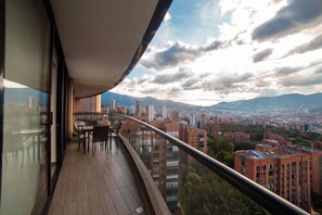 A balcony with a city view, including buildings and mountains. - Hotel Class Suites By Colclick (Medellín)