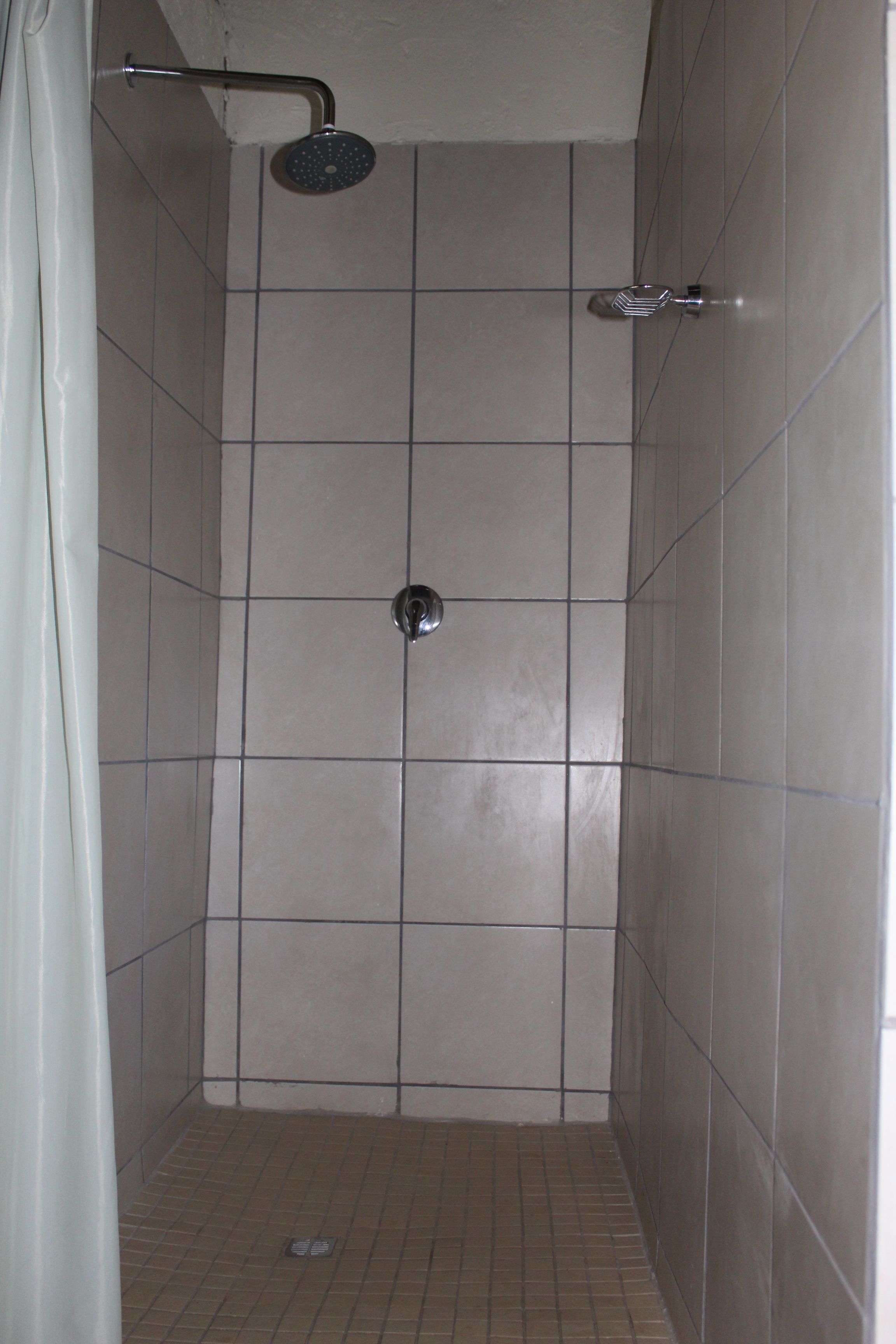 A small, tiled shower stall with a showerhead and a faucet.