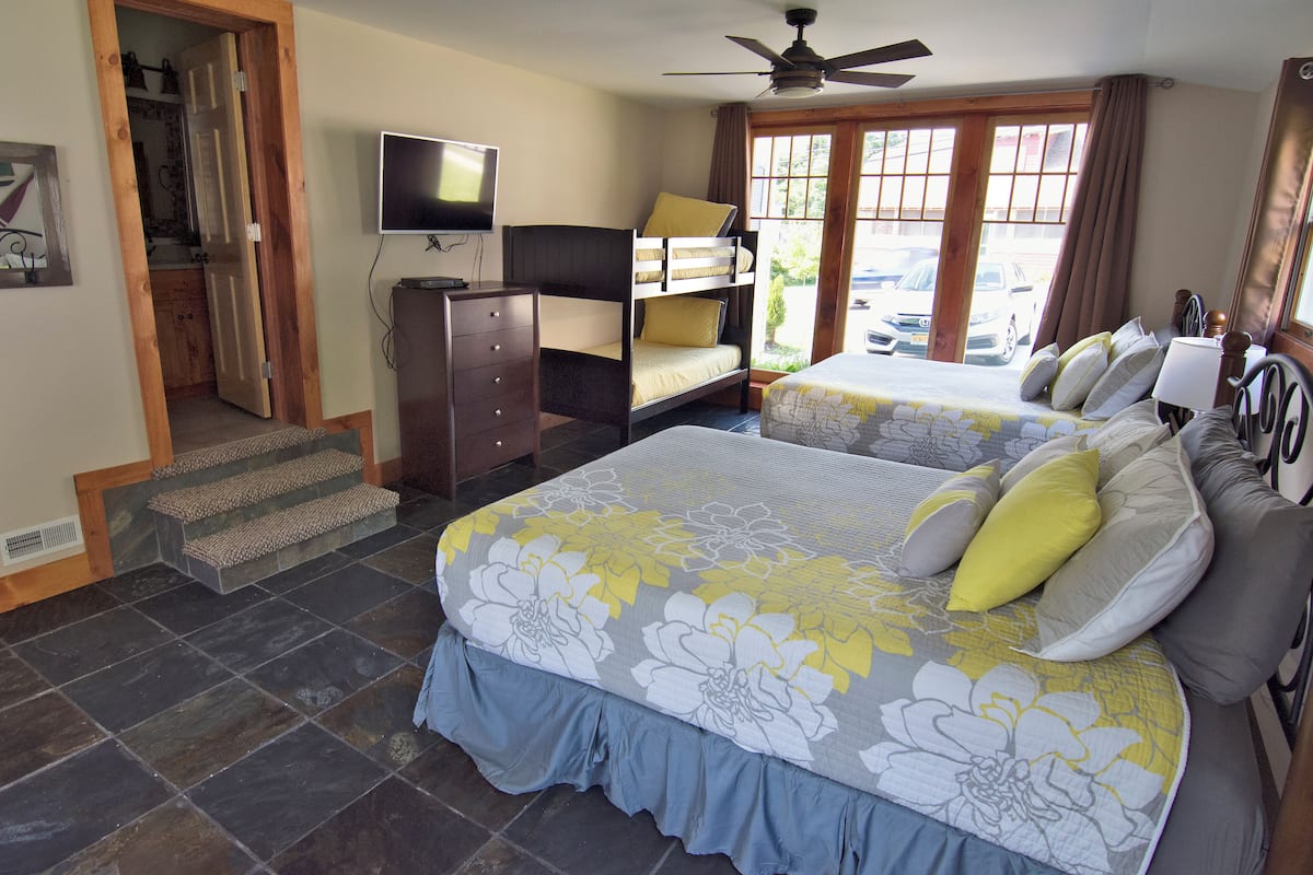 A bedroom with two beds, a TV, a dresser, and a ceiling fan.