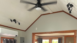 A bedroom with a large bed, a ceiling fan, an air conditioning unit, a window with curtains, and a wooden door. - Beach Cottages at Lake George (Lake George)
