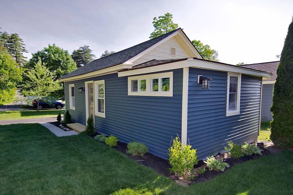 A single-story house with a gabled roof, a front porch, and a small front yard with young trees.
