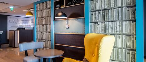 A modern interior with a yellow armchair, a small table, and a bookshelf filled with books.
