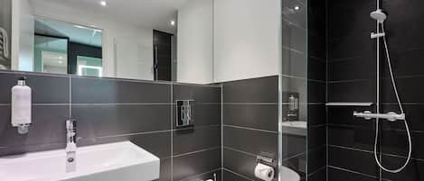 A modern bathroom with a white sink, toilet, and shower.