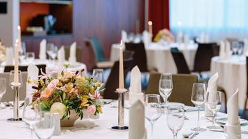 Un comedor con mesas dispuestas para una comida, velas y un centro de mesa floral.