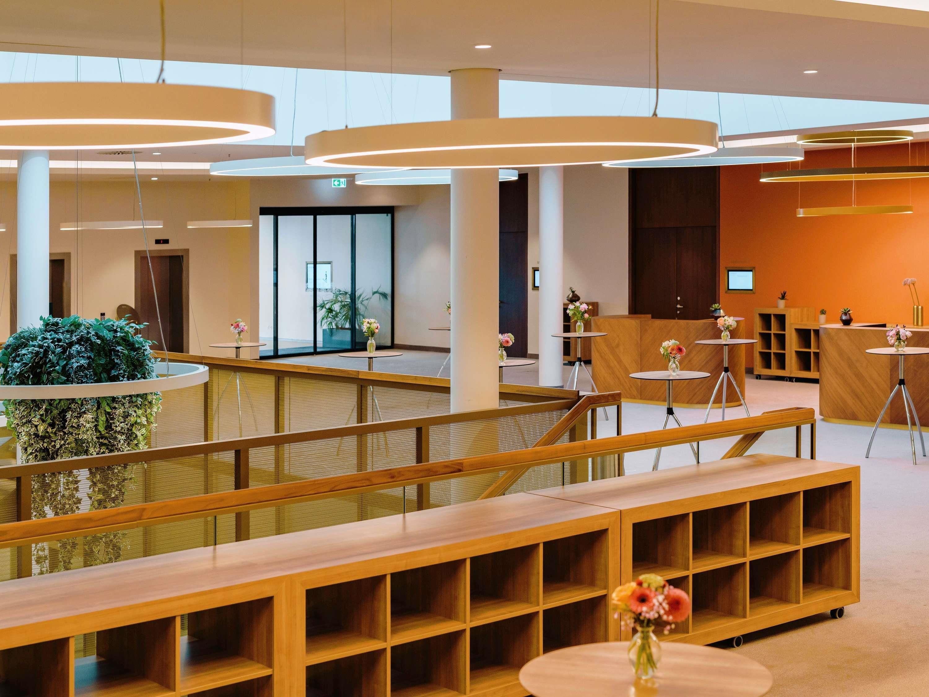 A modern hotel lobby with a central seating area, a reception desk, and a large plant.