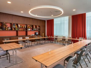 A conference room with a long table, chairs, a television, and a decorative shelf with various items. - Mövenpick Hotel Stuttgart Messe & Congress (Leinfelden-Echterdingen)