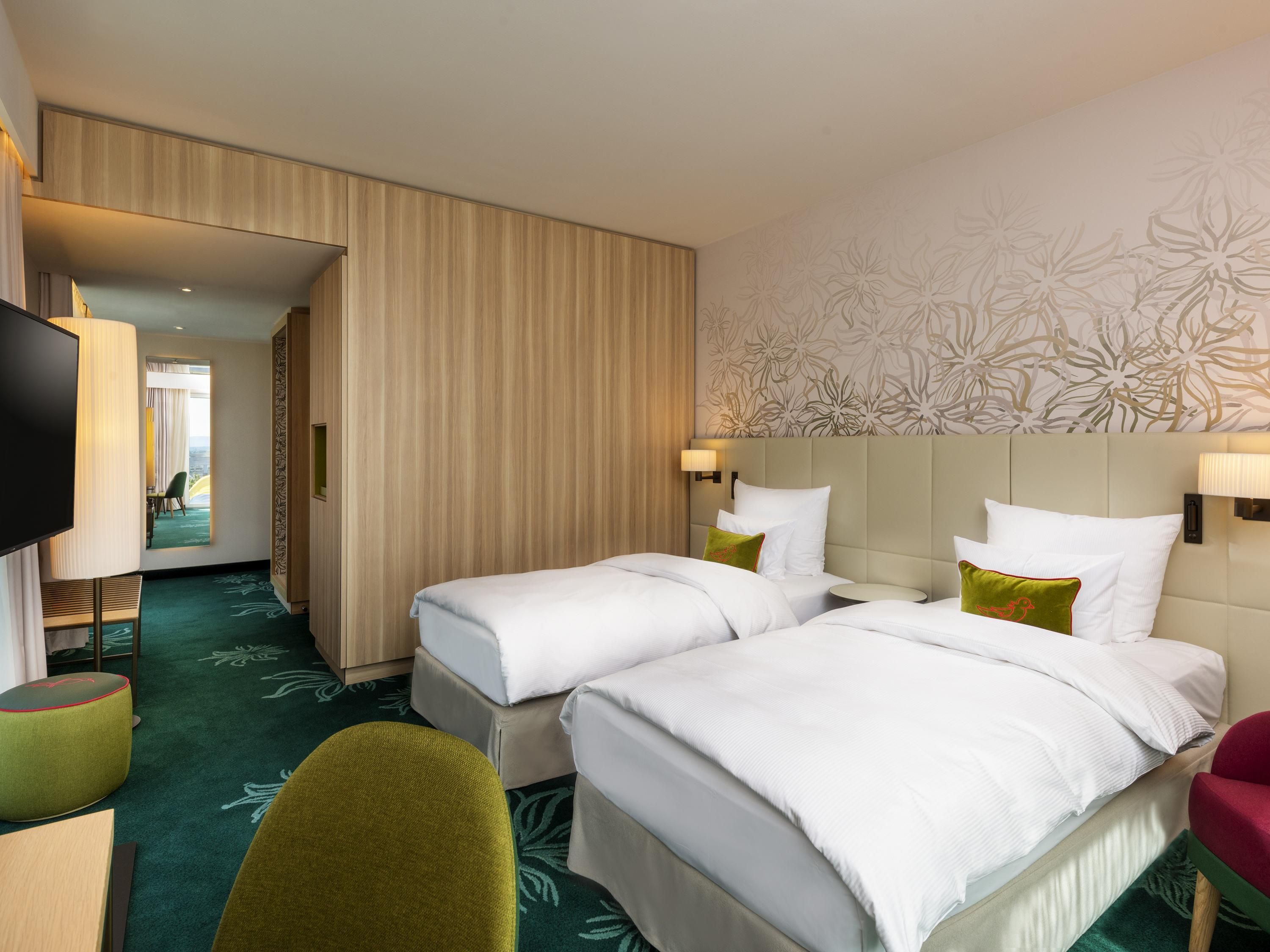 A hotel room with two beds, a TV, a desk, and a chair.