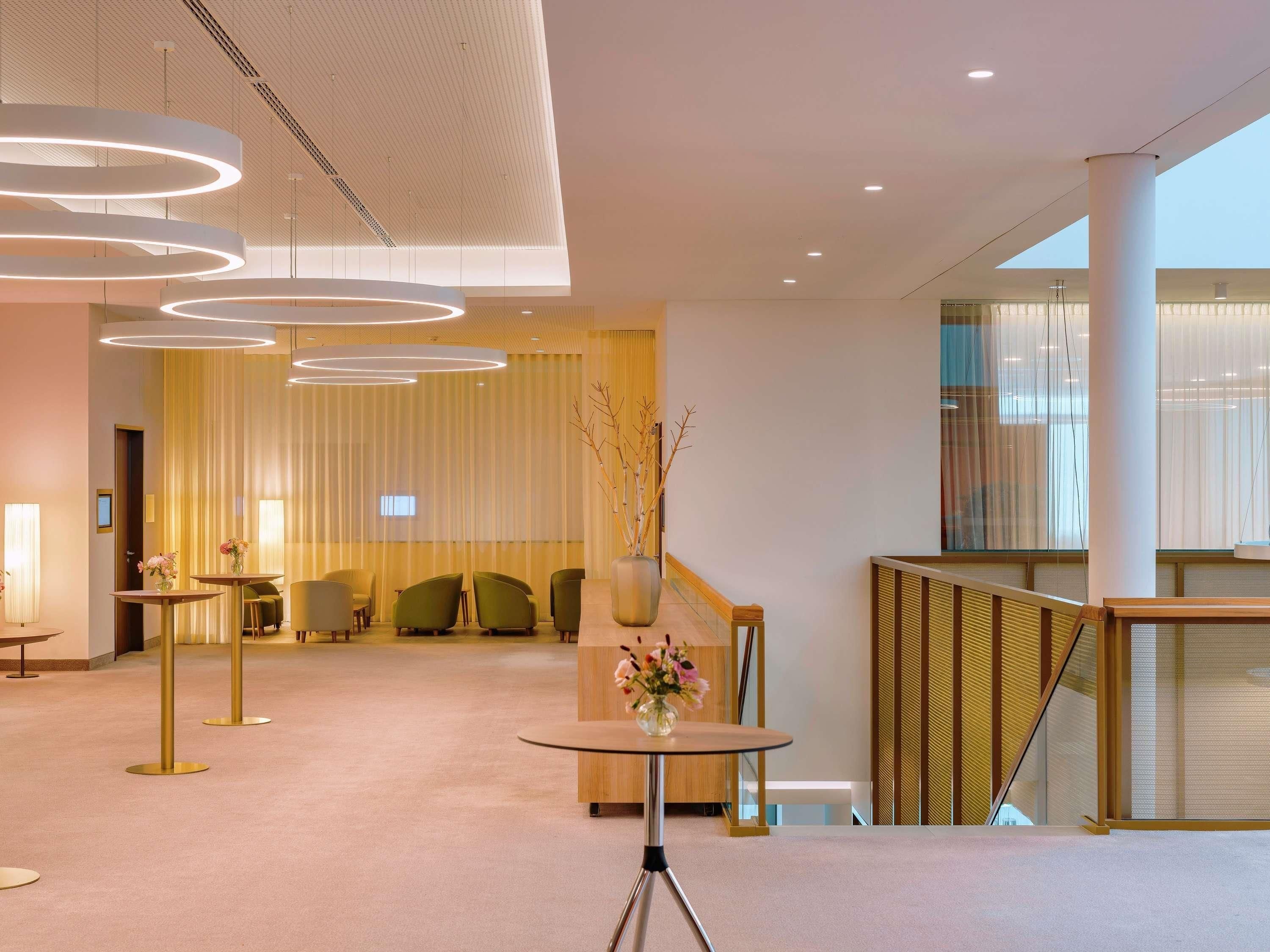 Eine moderne Lobby mit einer zentralen Sitzgelegenheit, einem Empfangstresen und einer Treppe.