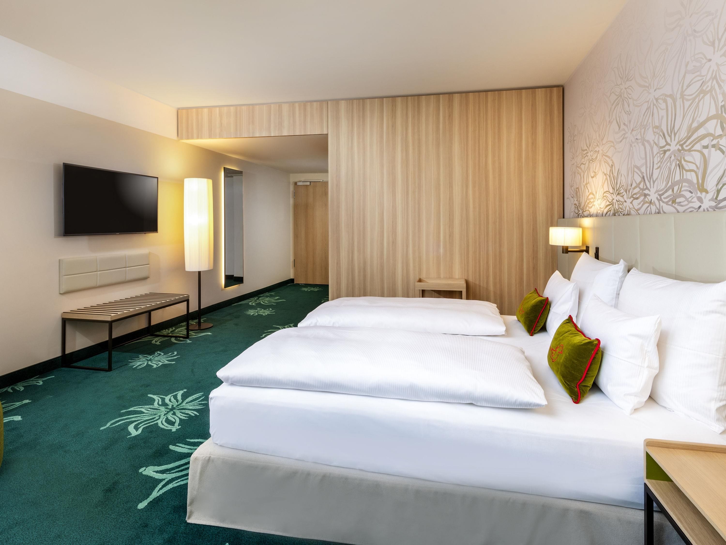 Una habitación de hotel con una cama, un televisor, una mesita de noche y una lámpara.