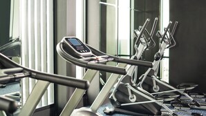 A row of stationary bikes in a gym with a control panel on the first bike. - Mövenpick Hotel Stuttgart Messe & Congress (Leinfelden-Echterdingen)