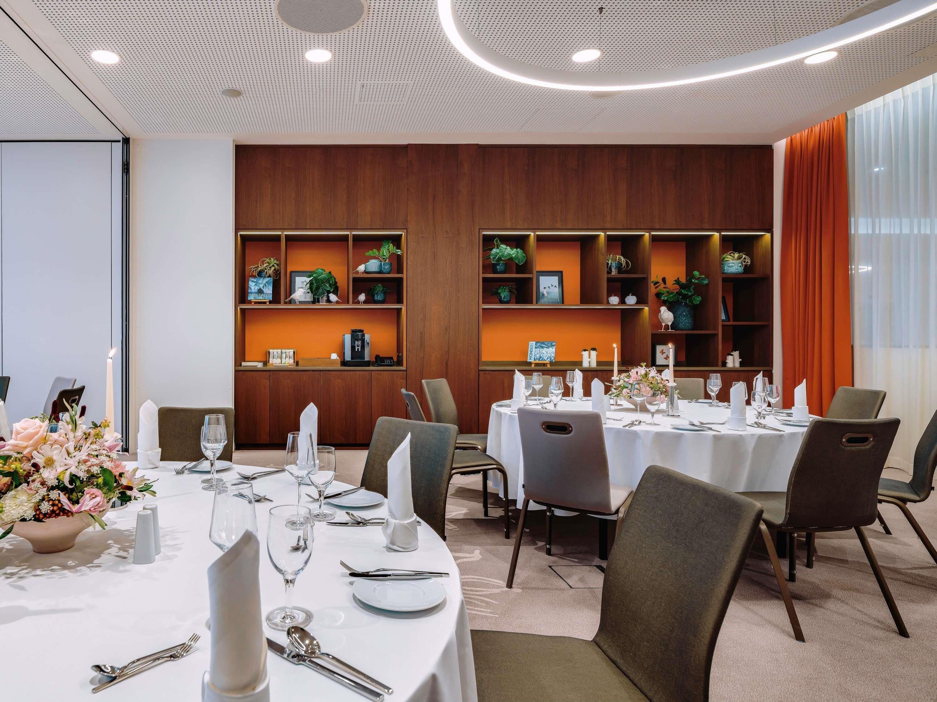 A conference room with round tables, white tablecloths, and chairs.