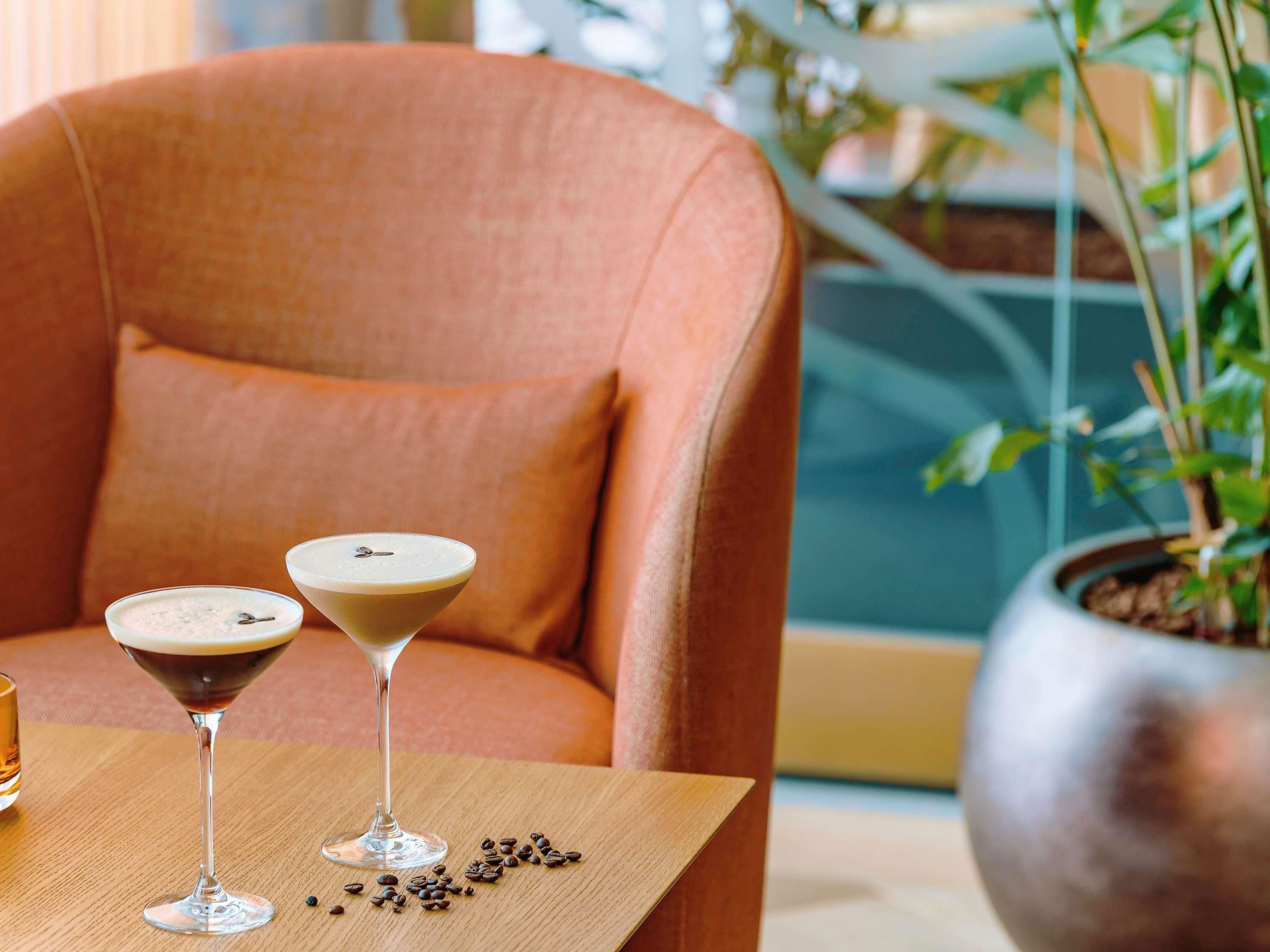 Two martini glasses on a wooden table with coffee beans scattered around.
