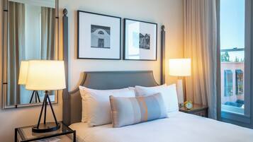 Une chambre d’hôtel comprenant un lit, deux lampes de chevet, une table de chevet avec une lampe, un miroir et deux tableaux encadrés accrochés au mur.