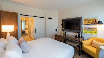 Une chambre d’hôtel avec un lit, une télévision, un canapé et un tableau au mur.