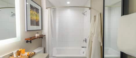 A modern bathroom with a bathtub, toilet, and a shower area.