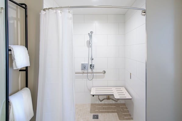 A shower with a handheld showerhead, a handheld showerhead, and a shower seat.