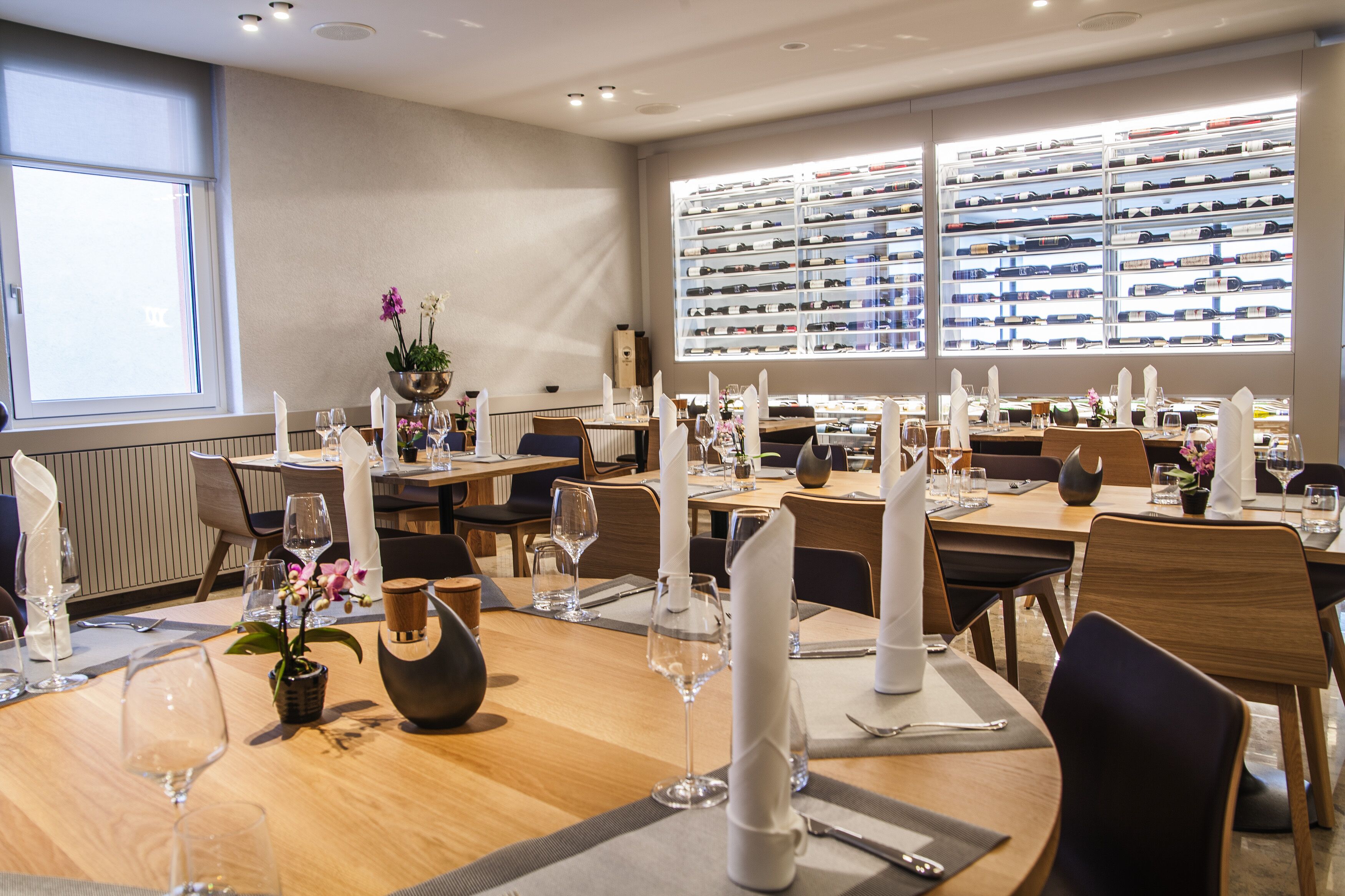 En restaurant med flere borde, et stort vinkort og udsigt over byen.