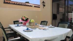 Un espace de restauration en plein air avec une table dressée pour quatre personnes, entourée de chaises.