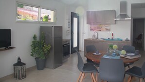 Une cuisine moderne comprenant un coin repas, un réfrigérateur, une cuisinière et un évier.