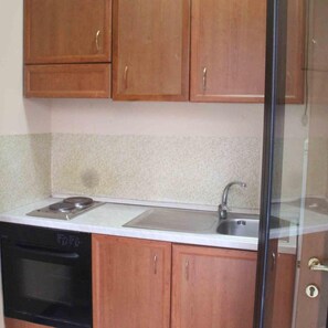 A kitchen with wooden cabinets, a stove, a sink, and a dishwasher. - Hotel Cristal (Bari)
