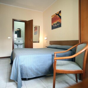 A bedroom with a bed, a chair, a bathroom with a mirror, and a painting on the wall. - Hotel Cristal (Bari)