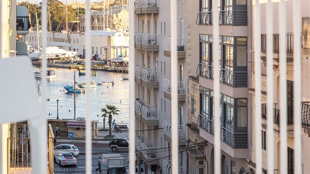 A balcony with a view of a marina and buildings. - Island Guesthouse (Gzira)