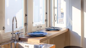 A kitchen with a built-in sink, a wooden countertop, and a small bar area with stools. - Island Guesthouse (Gzira)