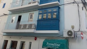 A multi-story building with balconies, a visible salon named 'Trendline', and a car parked in front.