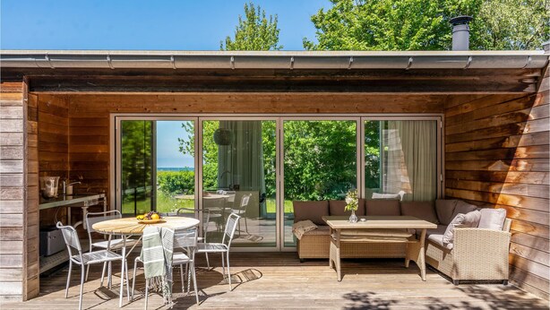 Una cabaña de madera con un patio que tiene una mesa redonda, sillas y un sofá.
