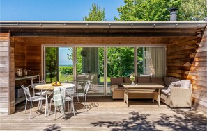 A wooden cabin with a patio area featuring a round table, chairs, and a sofa. - Cozy home in Dronningmølle with WiFi (Dronningmølle)