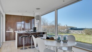 Una cocina moderna con una isla grande, taburetes de bar y una mesa de comedor con sillas.