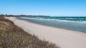 Una playa con cielos despejados, una orilla arenosa y una costa distante con edificios.