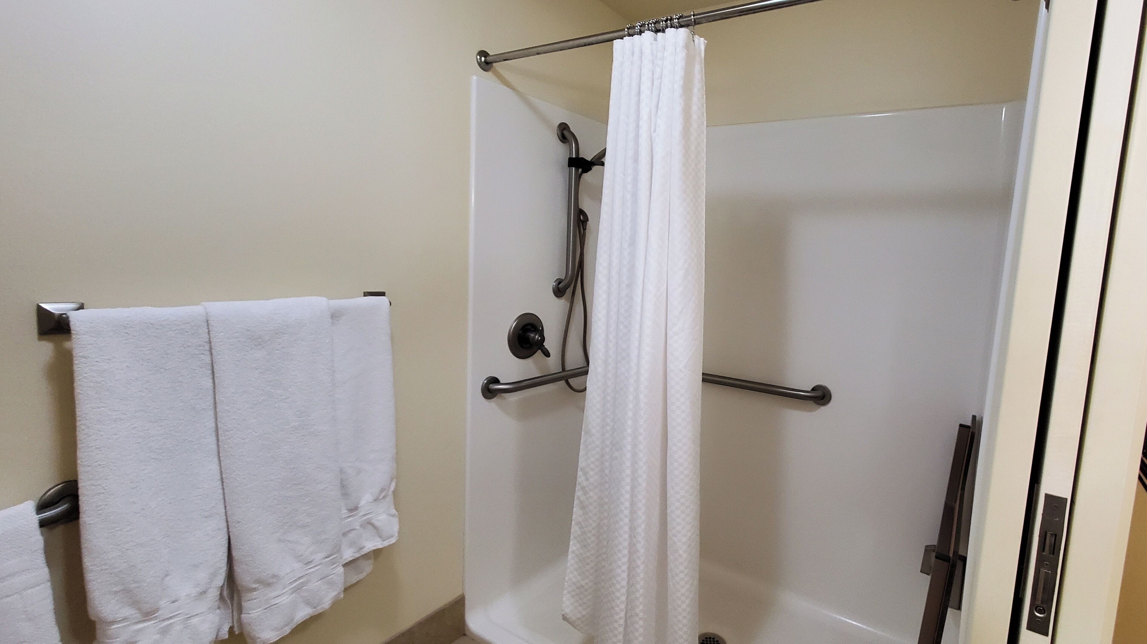 A bathroom with a shower, a towel rack, and a curtain.