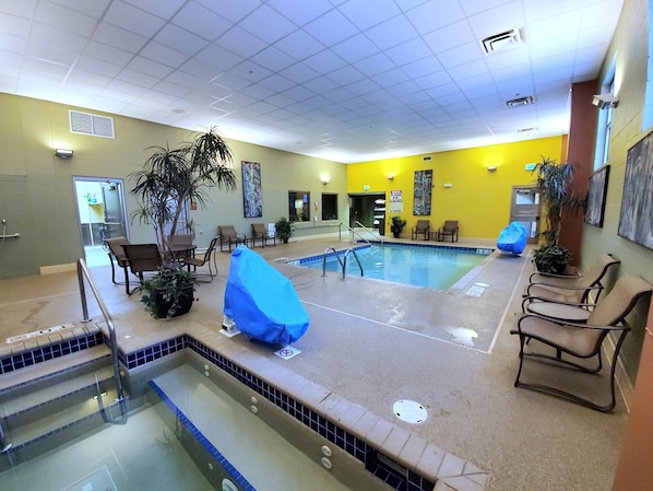 Un área de piscina con sillas y una zona de estar techada.