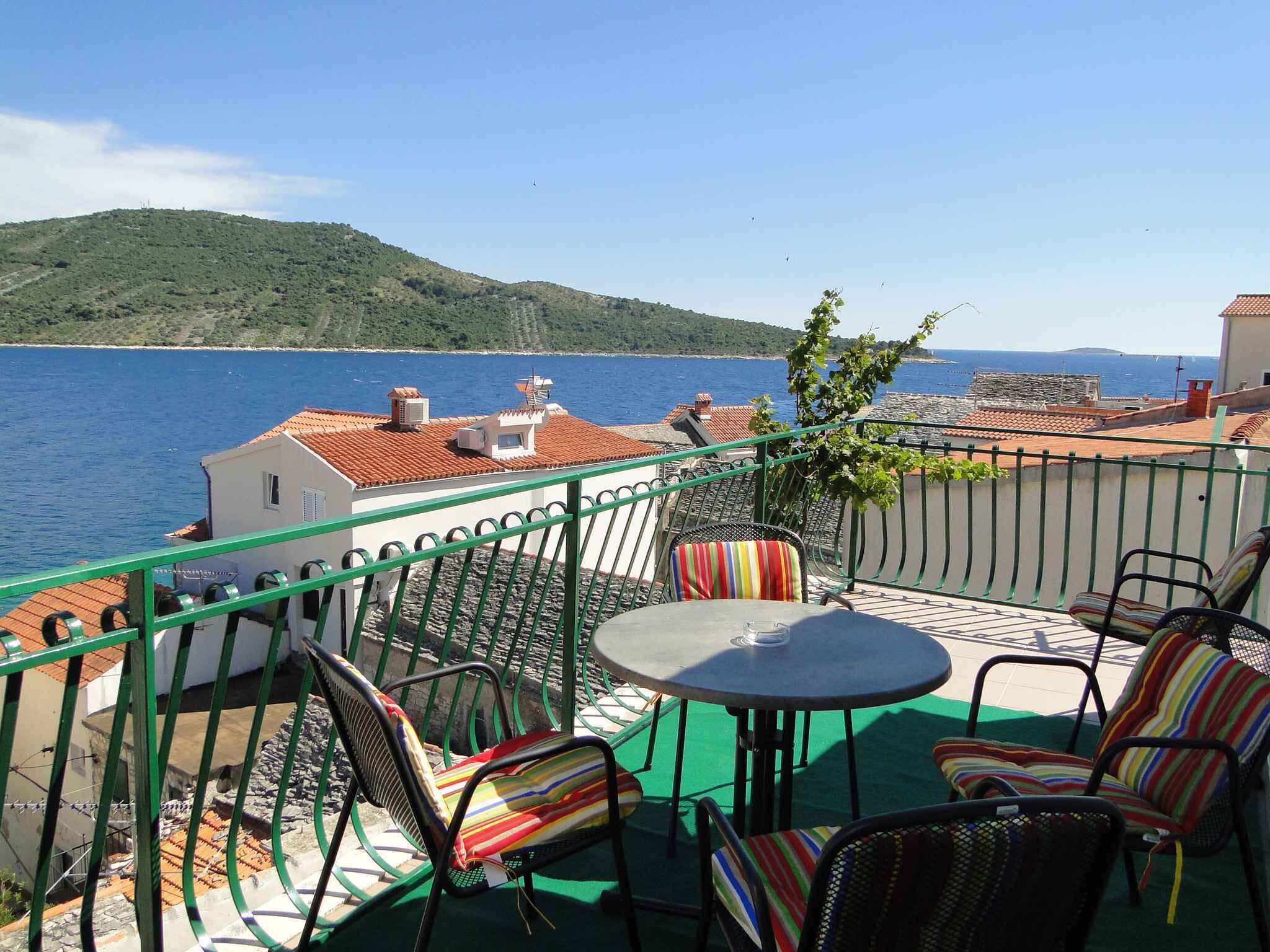 Un balcón con mesa y sillas que da a vistas de la costa.