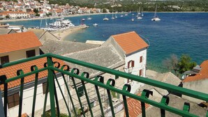 A coastal town with a marina, buildings with red-tiled roofs, and a clear blue sea.