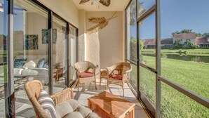 Un balcon spacieux, doté de meubles en osier, d’un ventilateur de plafond et offrant une vue sur un paysage verdoyant.