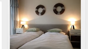 A double bed with two nightstands, each with a lamp, in a room with a neutral color scheme and two circular wall decorations.